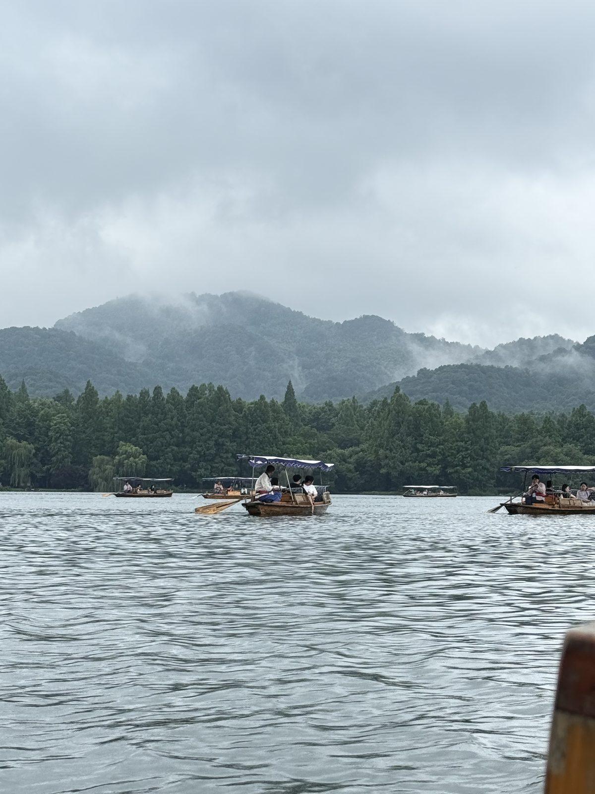Hand-rowed boats on West Lake, Hangzhou, with mist on the hills behind