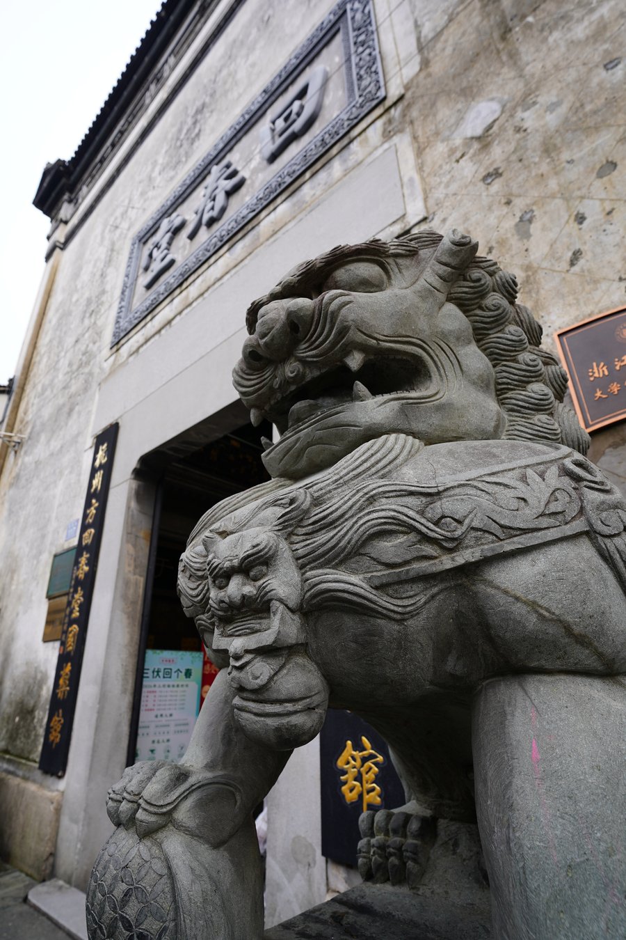 A carved stone guardian lion at the entrance to a Qinghefang courtyard