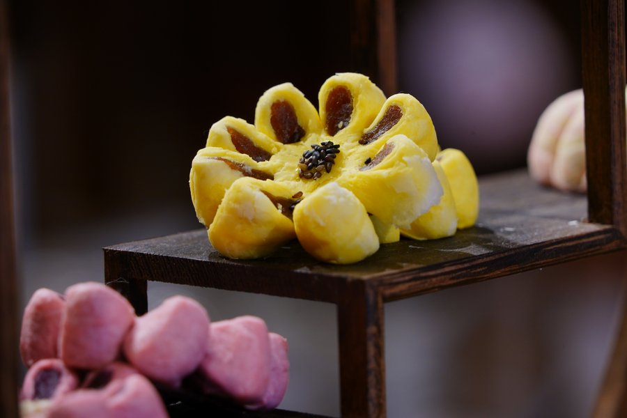 A hand-shaped flower pastry displayed on a small wooden stand