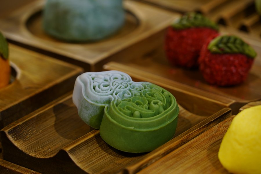 An assortment of colourful traditional Hangzhou pastries on a wooden tray