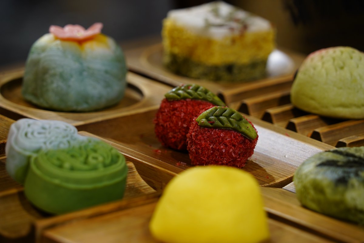 An assortment of colourful hand-shaped Hangzhou pastries on wooden trays
