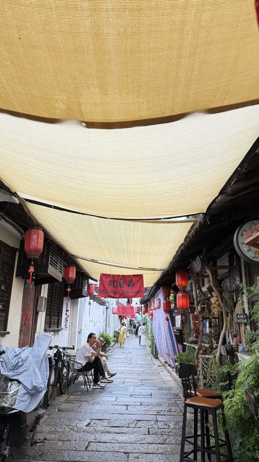 Red banners and lanterns strung above a flagstone shopping street