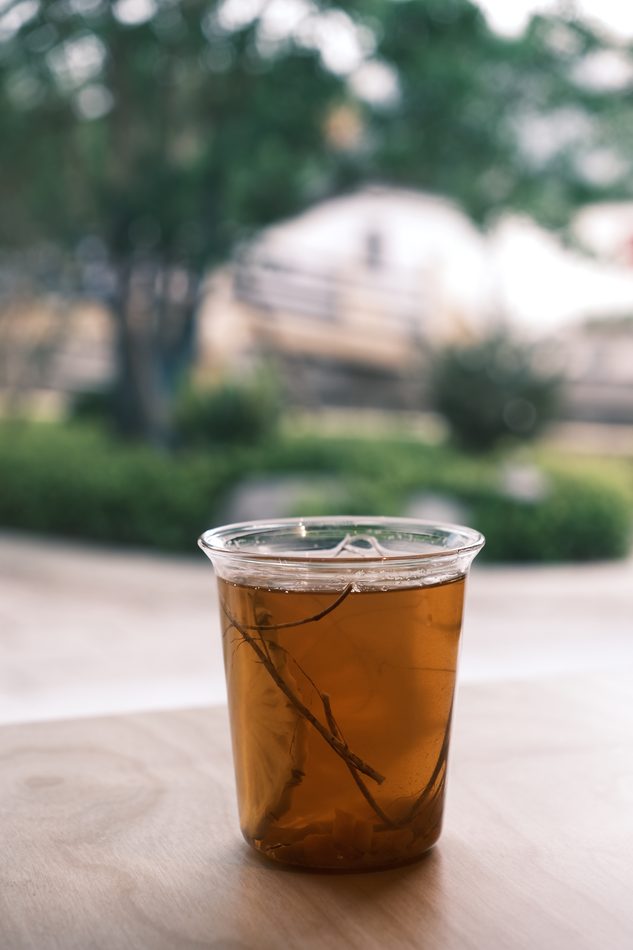 A cup of herbal tea with botanicals visible in the liquid