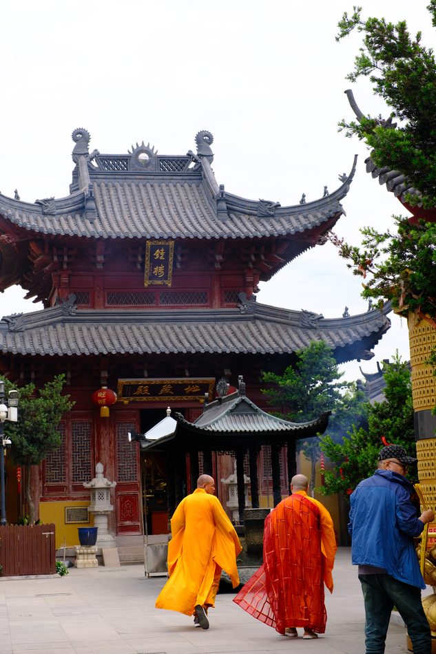 Monks in orange robes crossing a temple courtyard