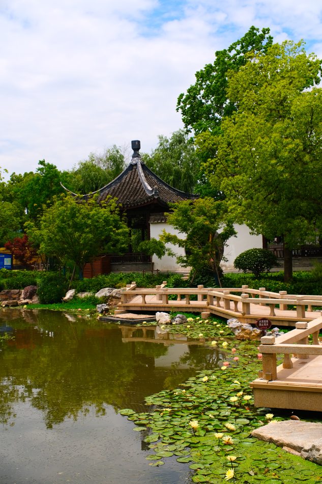 A temple garden pond with a pavilion and a low bridge