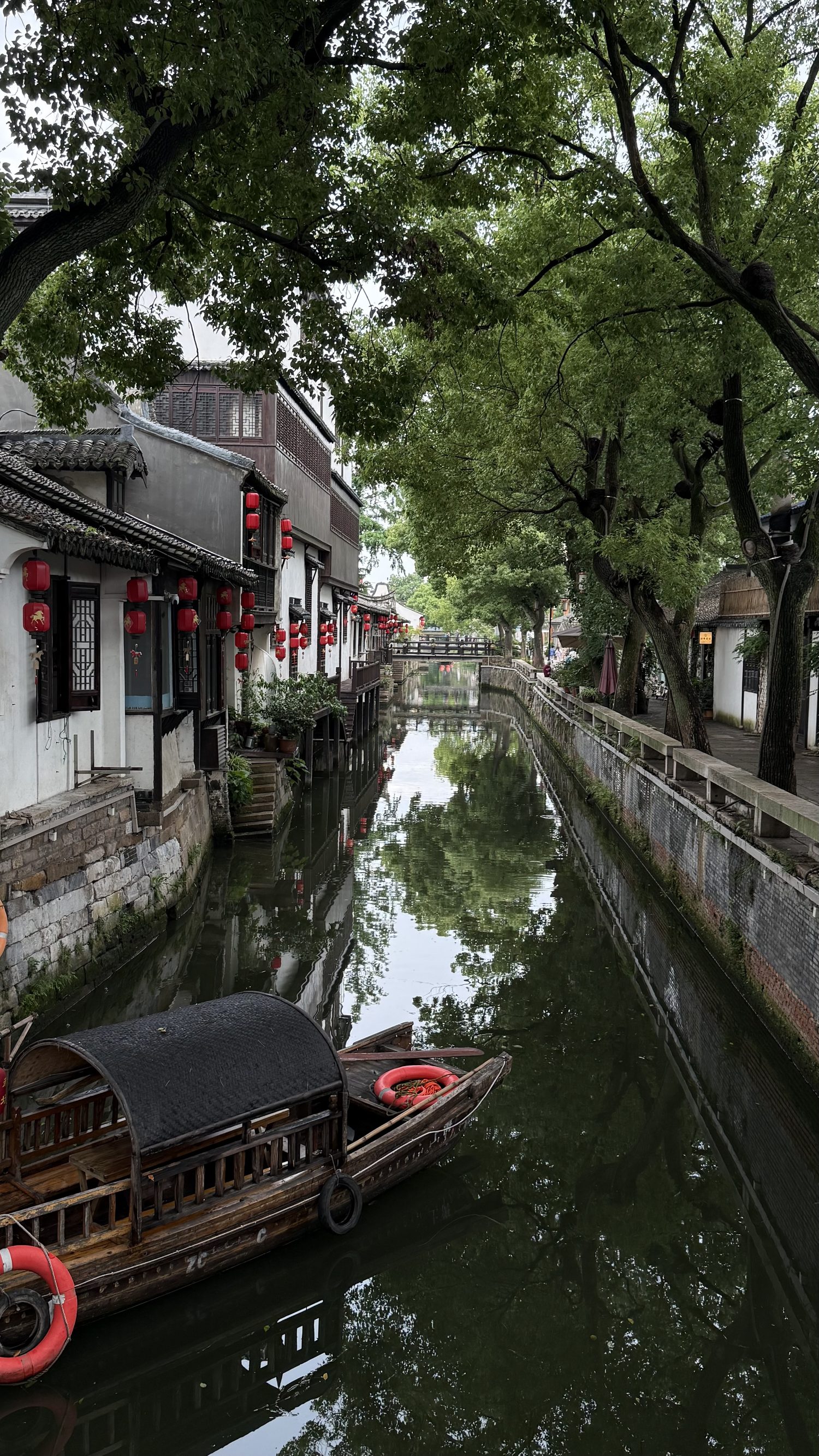A Xinchang canal lined with red lanterns, willows and a stone bridge