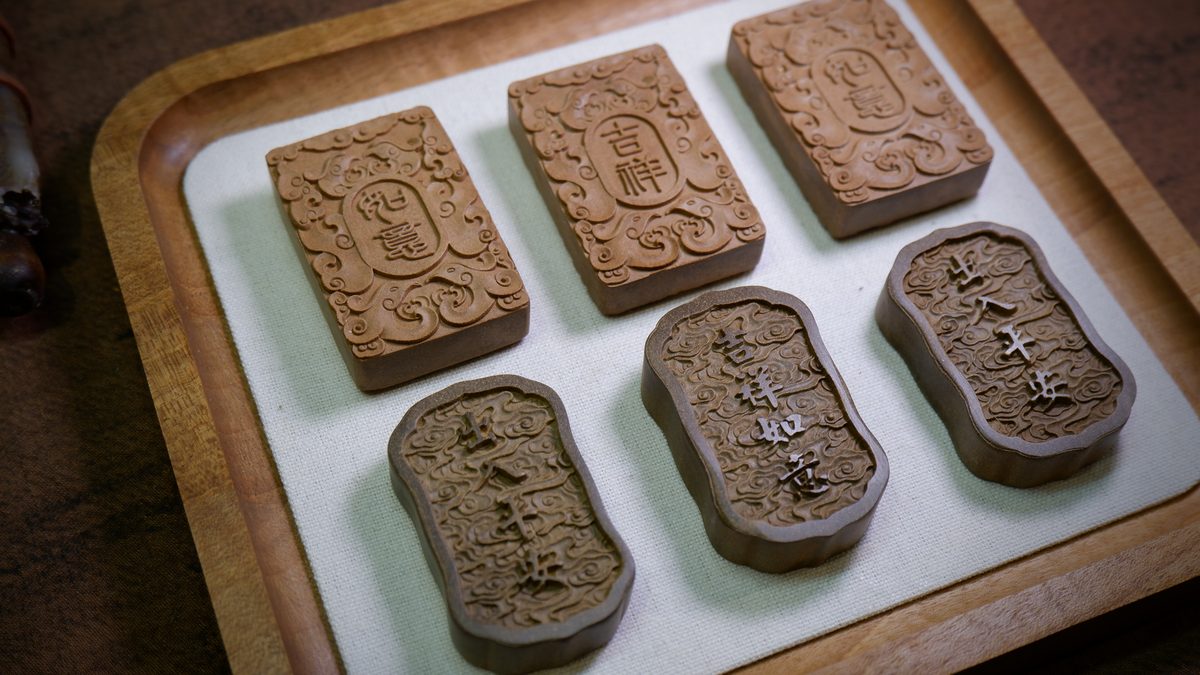 Six carved incense plaques laid out on a wooden tray