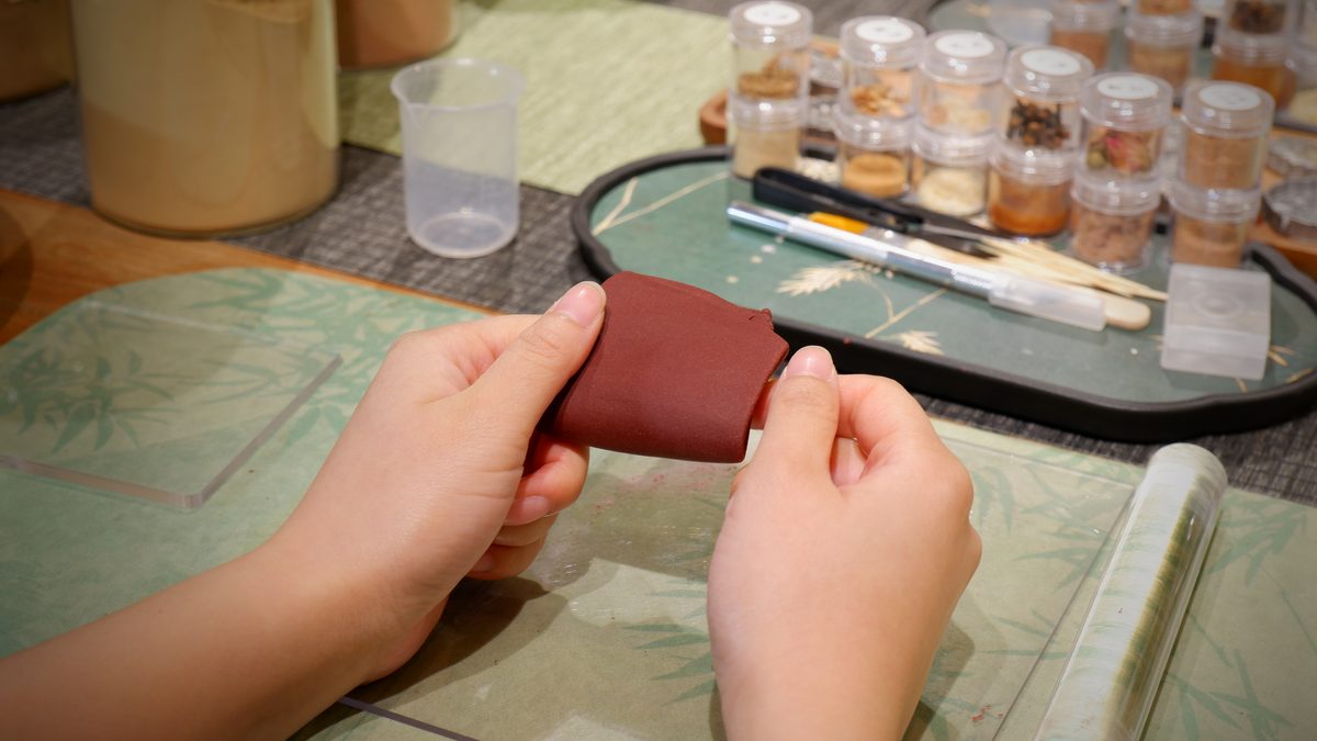 Hands rolling a block of dark red incense paste