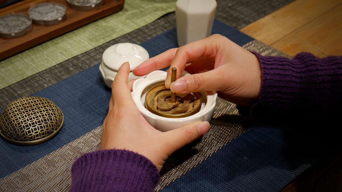 A completed incense spiral resting in a bowl on a blue cloth