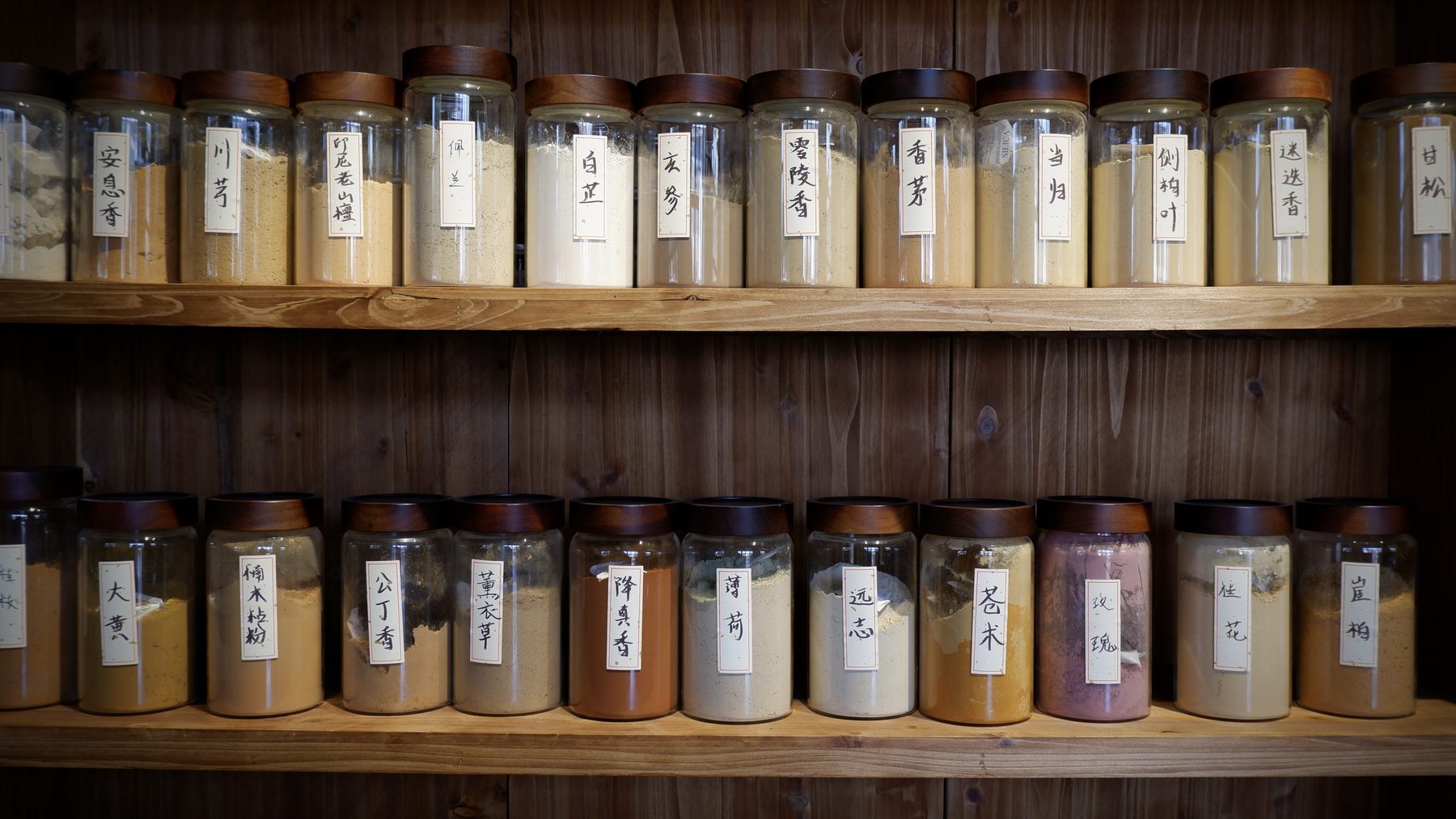 A wall of labelled glass jars holding raw incense materials