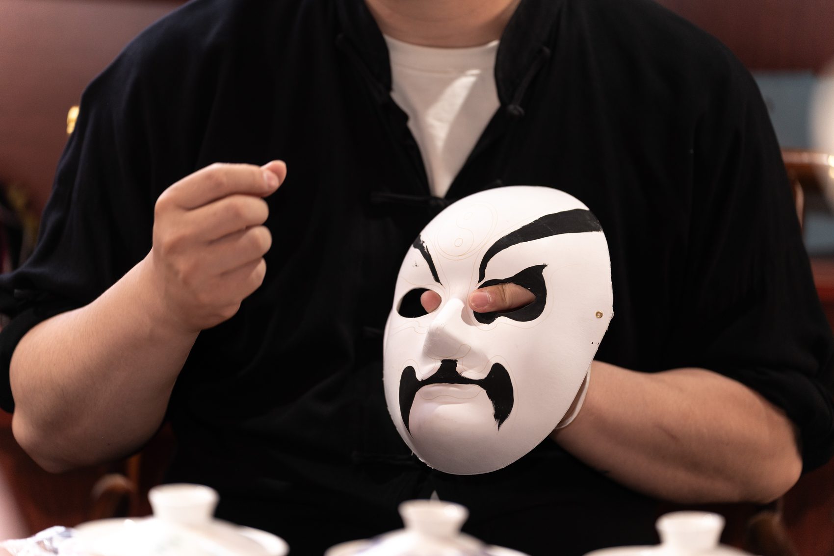 Hands holding a freshly painted opera mask