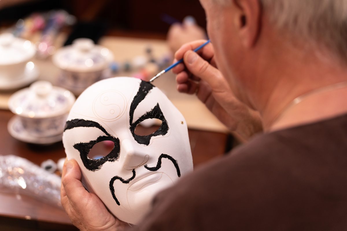 A brush drawing the black pattern onto a white opera mask