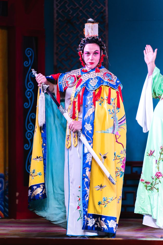 A Sichuan-opera performer in an embroidered robe holding a sword