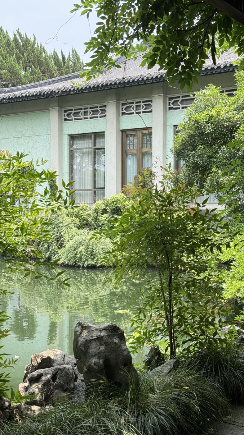 A traditional hotel building reflected in a still garden pond
