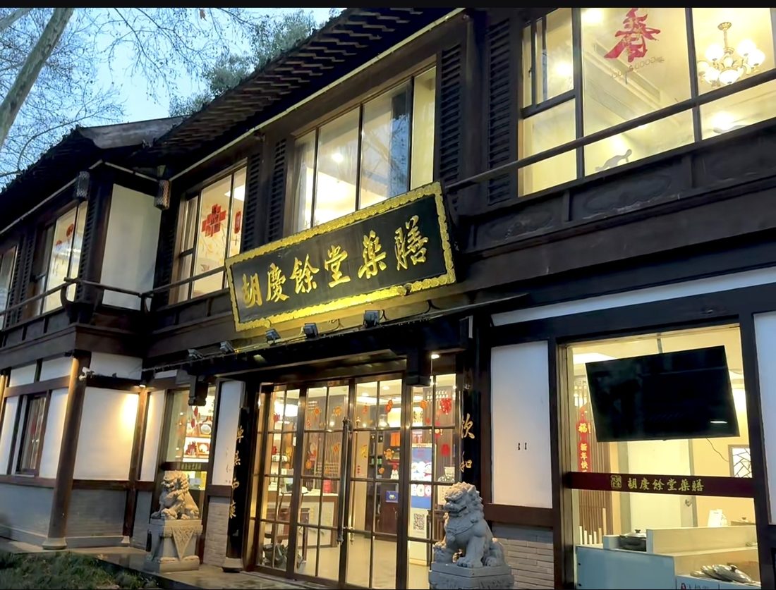 The lit shopfront of the Hu Qing Yu Tang pharmacy in Hangzhou's old quarter