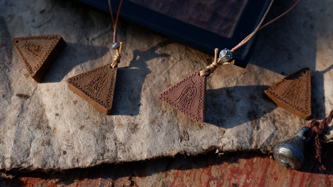 Four carved triangular incense plaques resting on stone with silk cords