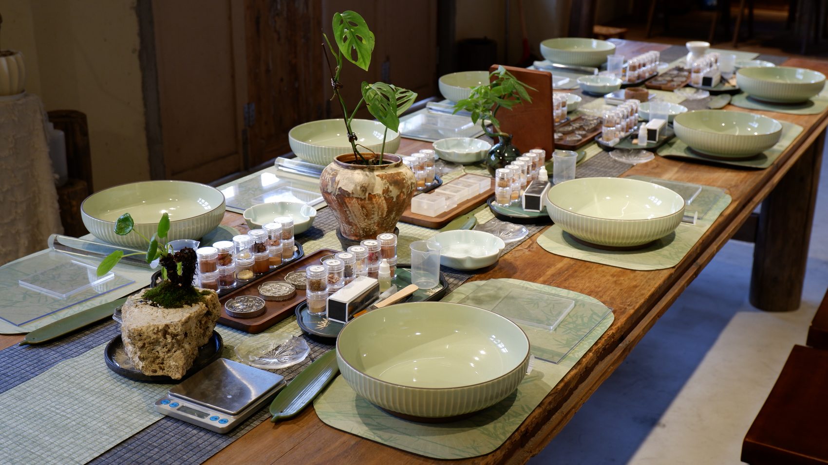 A long village worktable set with celadon bowls and material vials