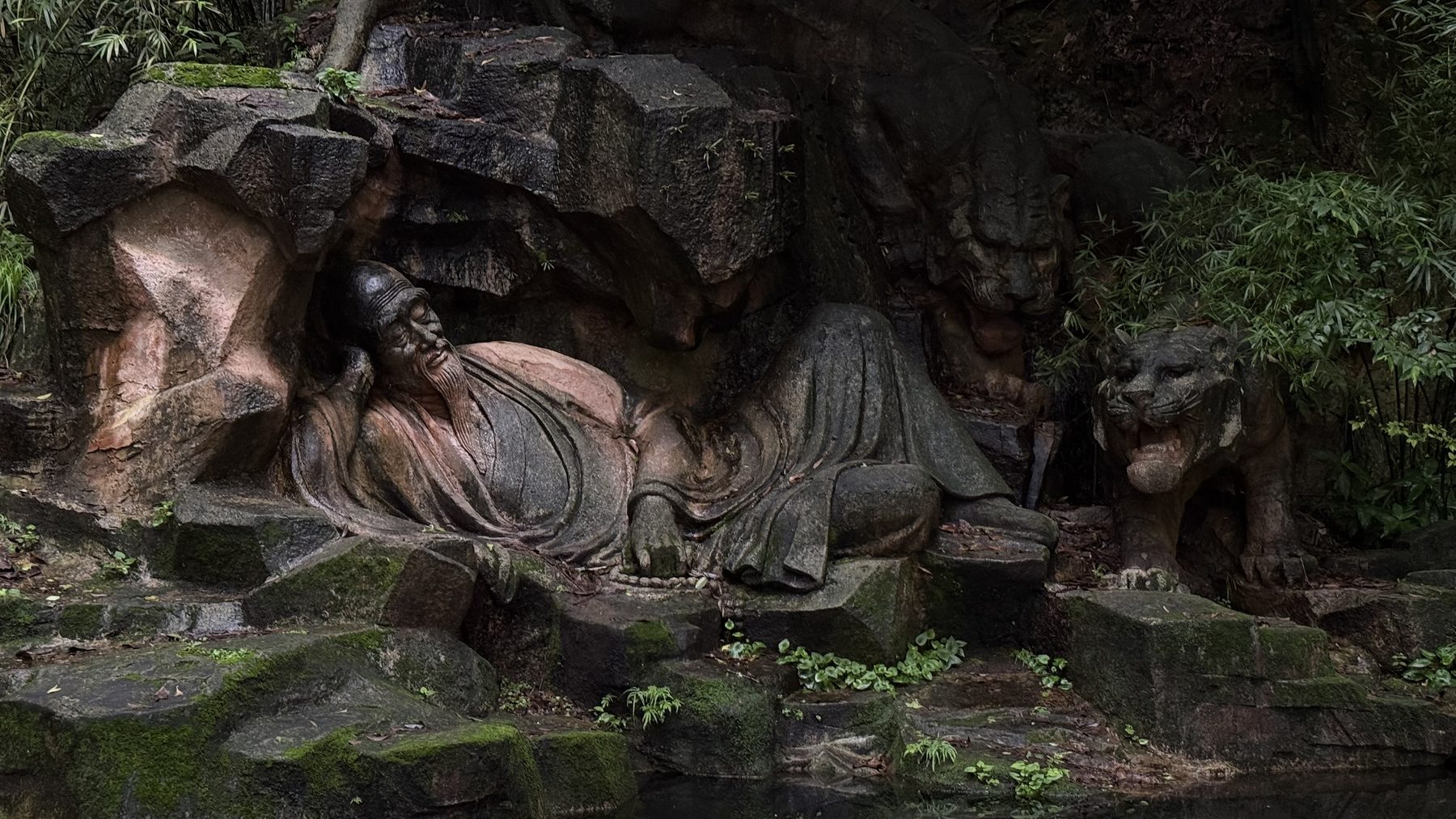 A rock-carved reclining Buddha above still water
