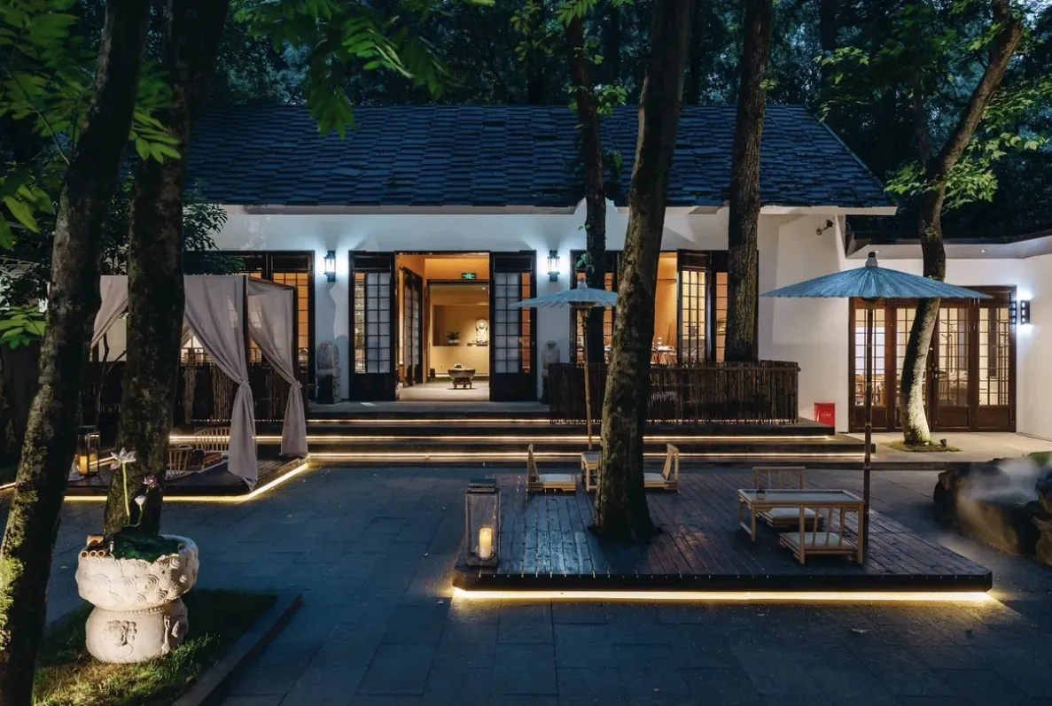 A courtyard restaurant lit at dusk, with outdoor seating among trees