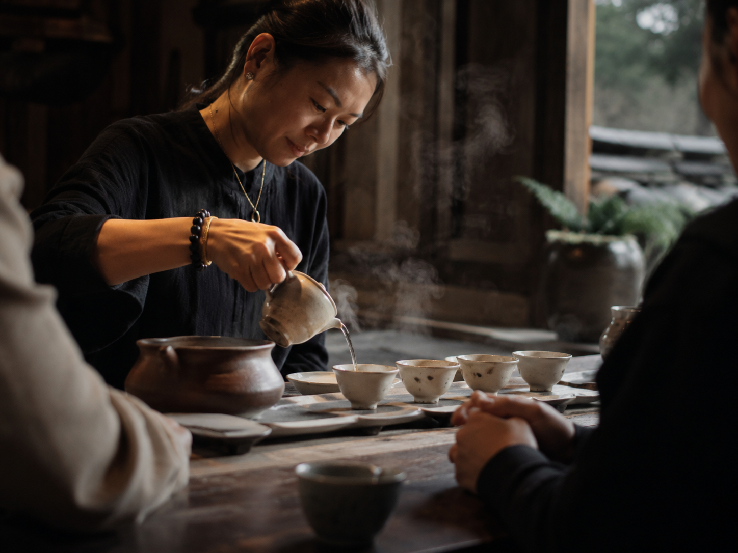 A tea master pouring tea, steam rising in warm light